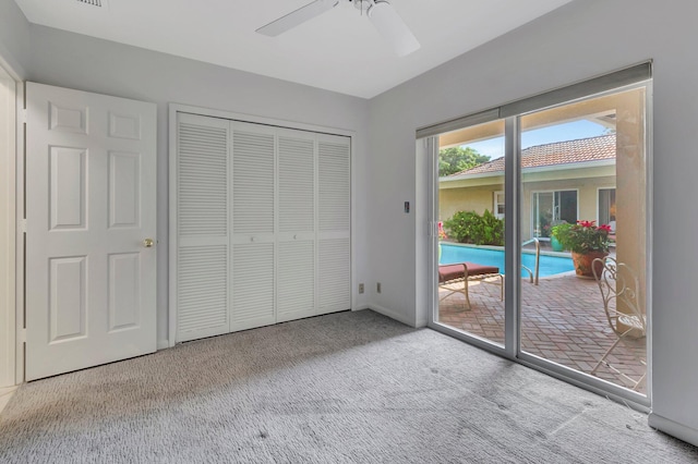 unfurnished bedroom with access to outside, ceiling fan, a closet, and light colored carpet