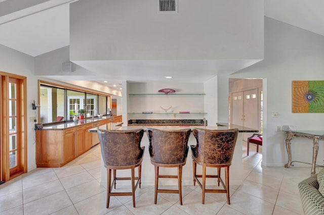 kitchen with kitchen peninsula, a kitchen breakfast bar, light tile patterned floors, and lofted ceiling