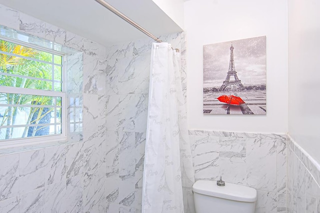 bathroom with toilet, tile walls, and curtained shower