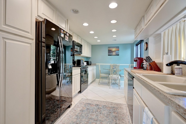 kitchen with sink, white cabinets, black appliances, and light tile patterned floors