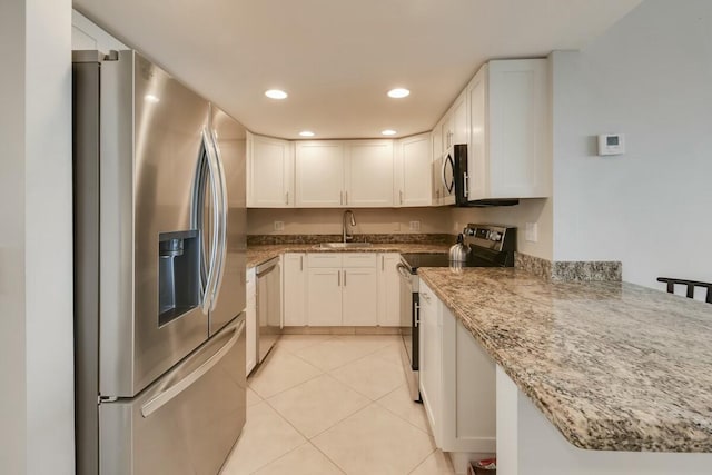 kitchen with white cabinets, appliances with stainless steel finishes, light stone countertops, and sink