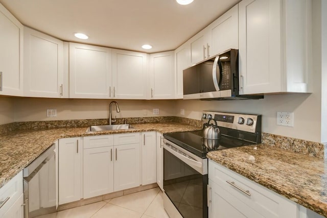 kitchen with sink, light stone countertops, light tile patterned floors, appliances with stainless steel finishes, and white cabinetry