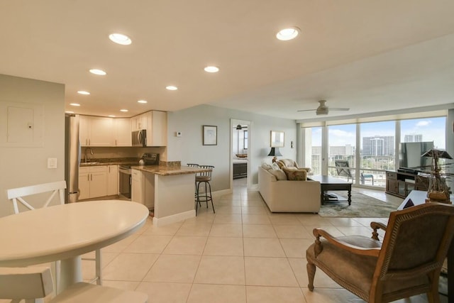 tiled living room with sink, expansive windows, and ceiling fan