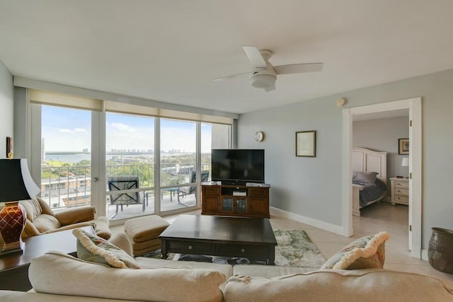 tiled living room featuring ceiling fan and a wall of windows