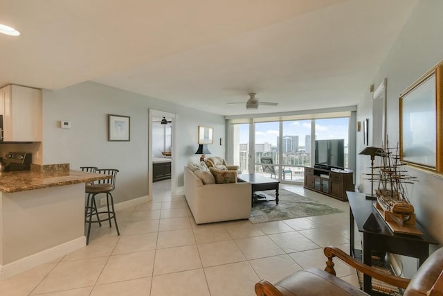 tiled living room featuring ceiling fan and expansive windows