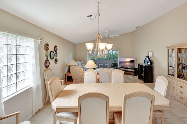 tiled dining space with ceiling fan with notable chandelier, vaulted ceiling, and plenty of natural light