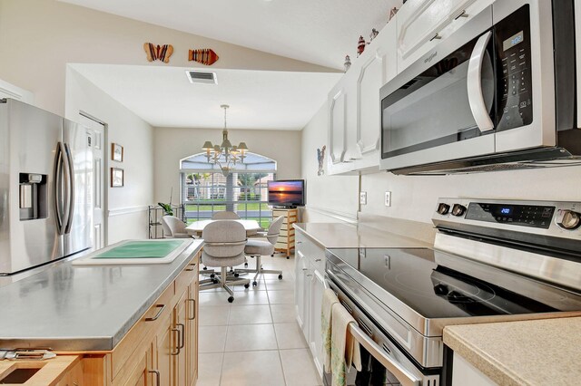 kitchen featuring hanging light fixtures, a chandelier, lofted ceiling, white cabinets, and appliances with stainless steel finishes