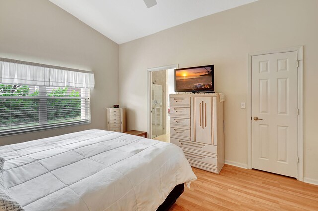 bedroom featuring light hardwood / wood-style floors, ensuite bath, ceiling fan, and lofted ceiling