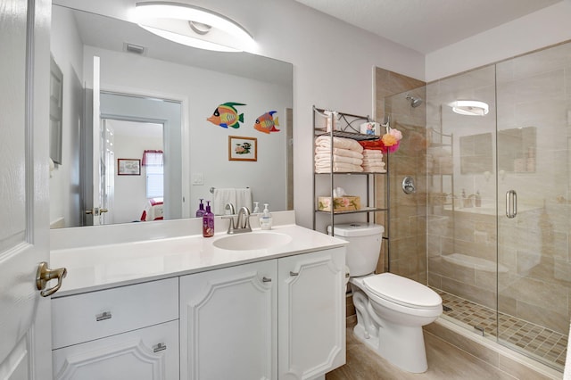 bathroom featuring tile patterned floors, vanity, toilet, and a shower with door