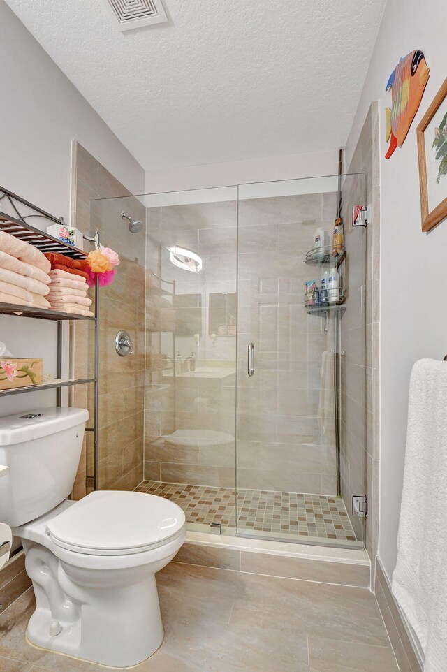 bathroom featuring an enclosed shower, tile patterned flooring, toilet, and a textured ceiling