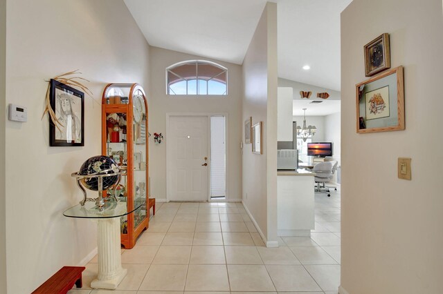 tiled foyer entrance with an inviting chandelier and vaulted ceiling