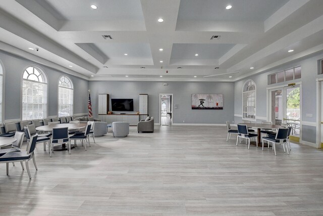 dining space featuring a raised ceiling, light wood-type flooring, and a towering ceiling