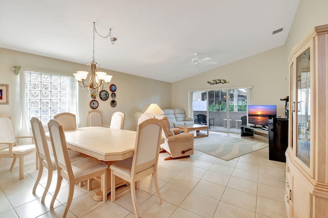 dining space with ceiling fan with notable chandelier, light tile patterned floors, and vaulted ceiling