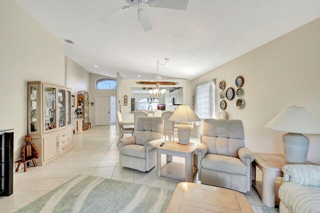 living room with vaulted ceiling, light tile patterned floors, and ceiling fan with notable chandelier