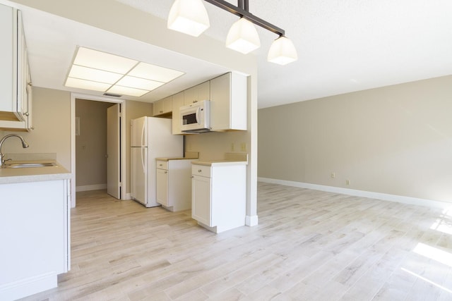 kitchen with white cabinetry, white appliances, decorative light fixtures, and sink