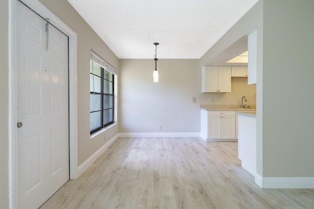 unfurnished dining area featuring sink and light hardwood / wood-style floors