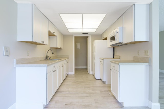 kitchen with sink, white cabinets, white appliances, and light hardwood / wood-style floors