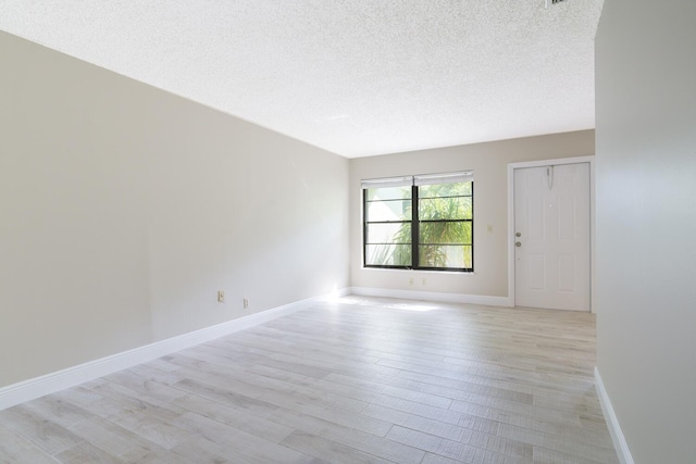 unfurnished room with a textured ceiling and light wood-type flooring