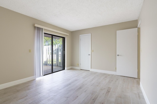 spare room with a textured ceiling and light wood-type flooring