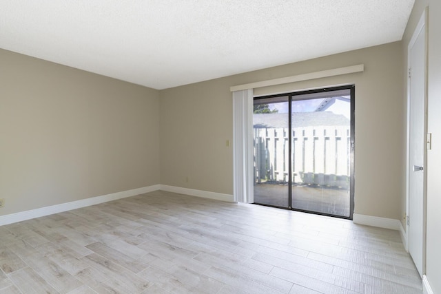 empty room with a textured ceiling and light wood-type flooring