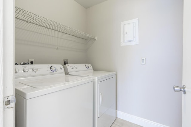 laundry room featuring electric panel, light hardwood / wood-style floors, and washer and dryer