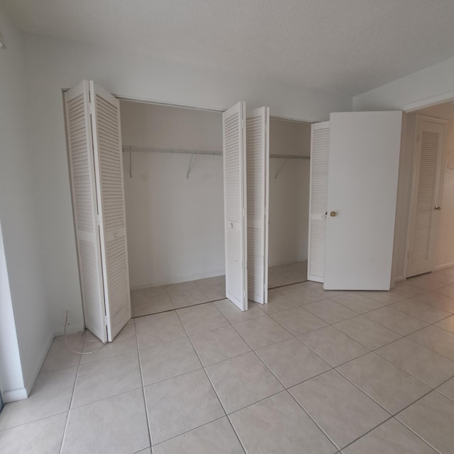 unfurnished bedroom with light tile patterned floors and two closets