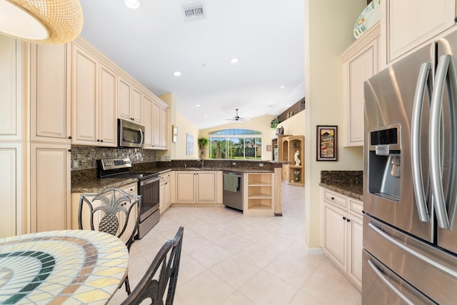 kitchen with stainless steel appliances, light tile patterned floors, dark stone countertops, ceiling fan, and sink