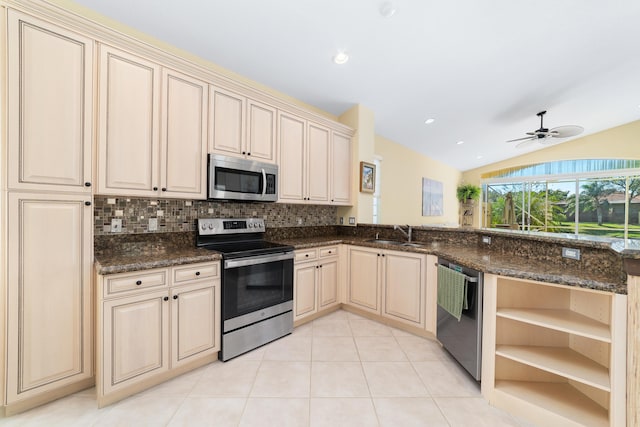 kitchen featuring vaulted ceiling, stainless steel appliances, dark stone countertops, ceiling fan, and sink