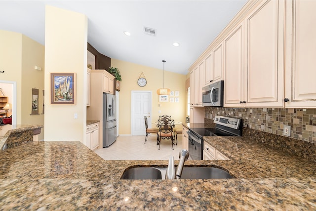 kitchen featuring stainless steel appliances, lofted ceiling, tasteful backsplash, dark stone counters, and pendant lighting