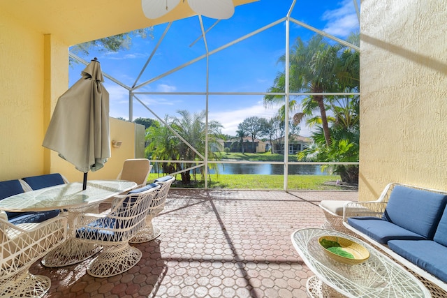 view of patio / terrace featuring ceiling fan, glass enclosure, and a water view