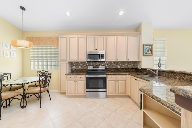 kitchen with sink, decorative backsplash, dark stone counters, pendant lighting, and appliances with stainless steel finishes