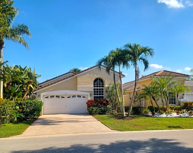 mediterranean / spanish-style home featuring a front lawn and a garage