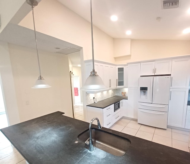 kitchen with white cabinetry, stainless steel microwave, white fridge with ice dispenser, pendant lighting, and sink