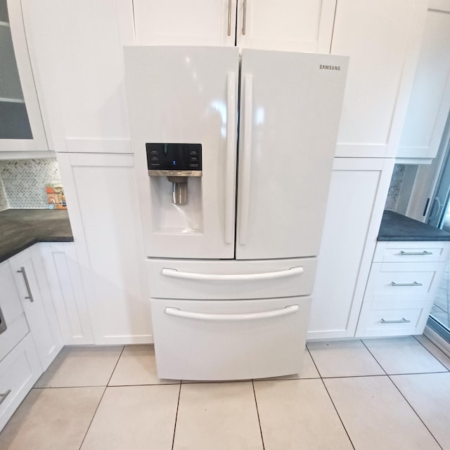 kitchen with light tile patterned flooring, white cabinetry, decorative backsplash, and white fridge with ice dispenser