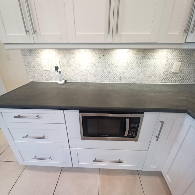 kitchen featuring decorative backsplash, white cabinets, and light tile patterned flooring