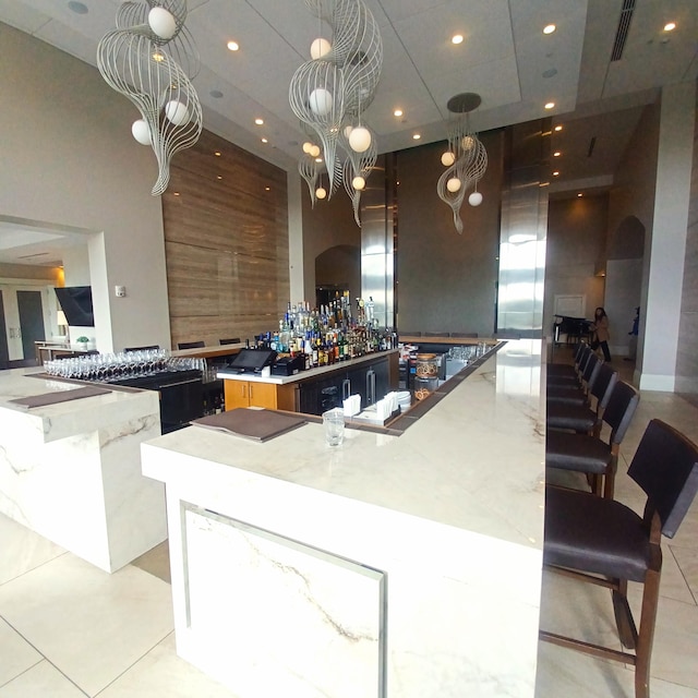 kitchen with an inviting chandelier, light tile patterned flooring, a high ceiling, and a spacious island