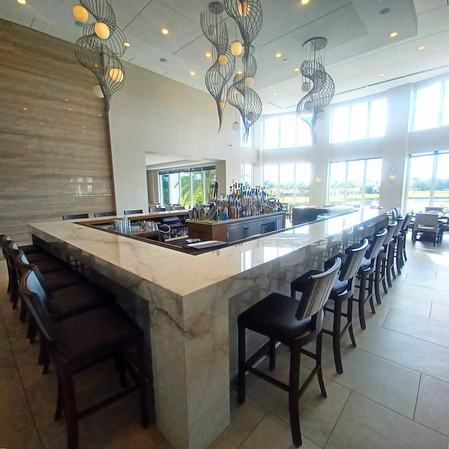 kitchen featuring a breakfast bar, pendant lighting, tile patterned floors, and a towering ceiling