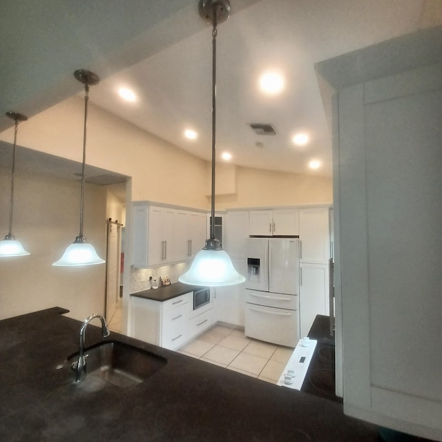 kitchen featuring vaulted ceiling, pendant lighting, sink, white cabinets, and white fridge with ice dispenser