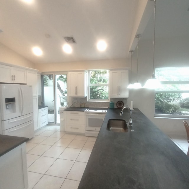 kitchen with light tile patterned floors, white cabinetry, white appliances, hanging light fixtures, and sink