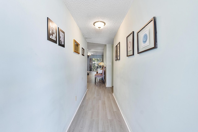 hallway featuring light wood-type flooring and a textured ceiling