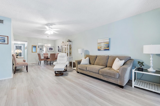 living room with ceiling fan with notable chandelier, light hardwood / wood-style floors, and a textured ceiling