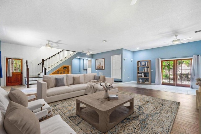 living room with french doors, a textured ceiling, and light wood-type flooring