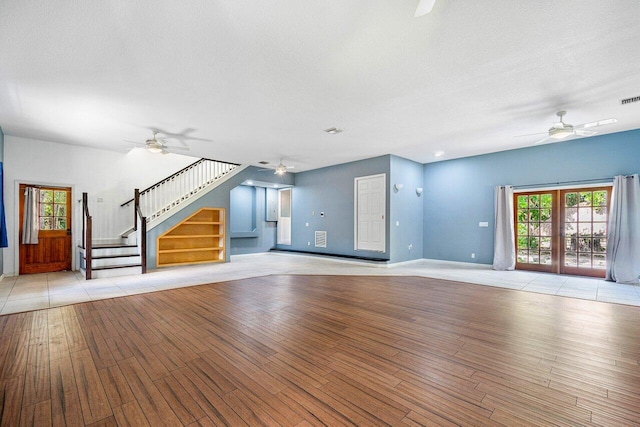 unfurnished living room featuring french doors, a textured ceiling, and light hardwood / wood-style flooring