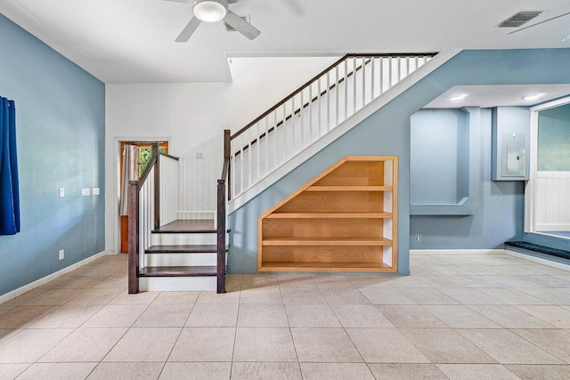 staircase featuring electric panel, tile patterned floors, and ceiling fan