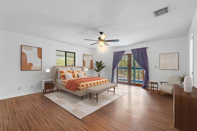 bedroom with access to outside, multiple windows, ceiling fan, and wood-type flooring