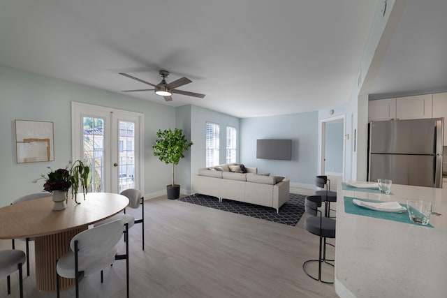 dining space with a wealth of natural light, ceiling fan, french doors, and light hardwood / wood-style floors