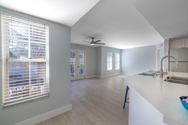 kitchen with ceiling fan, french doors, a kitchen bar, sink, and light hardwood / wood-style flooring