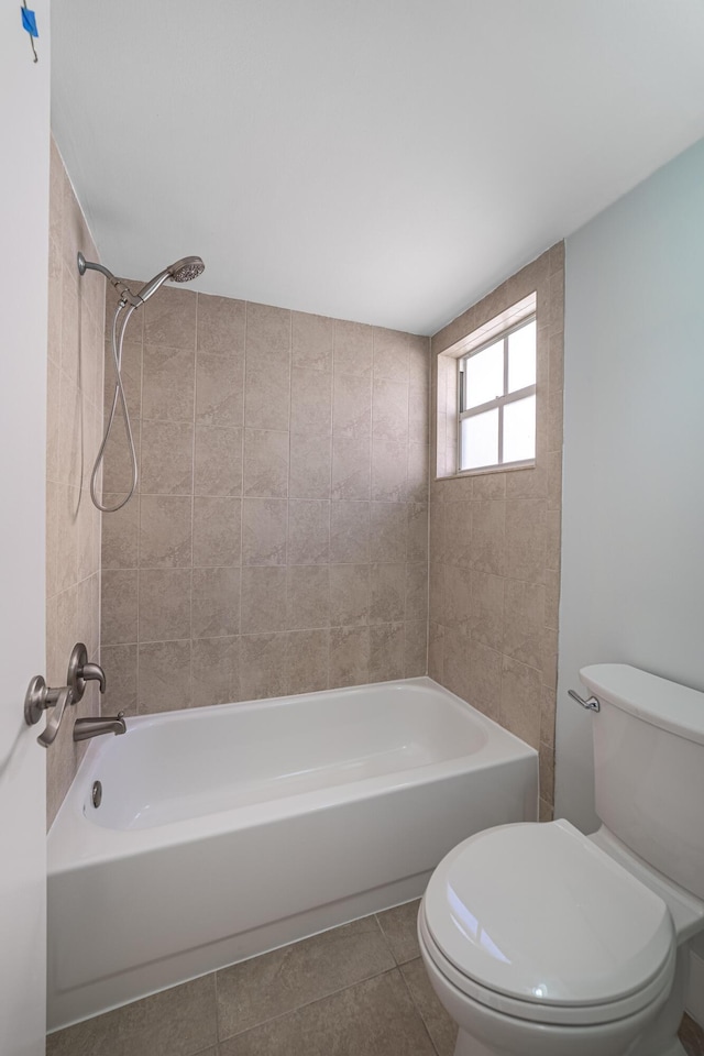 bathroom featuring toilet, tiled shower / bath combo, and tile patterned floors