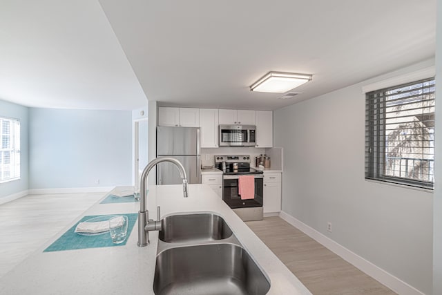 kitchen featuring appliances with stainless steel finishes, light hardwood / wood-style floors, white cabinetry, and sink