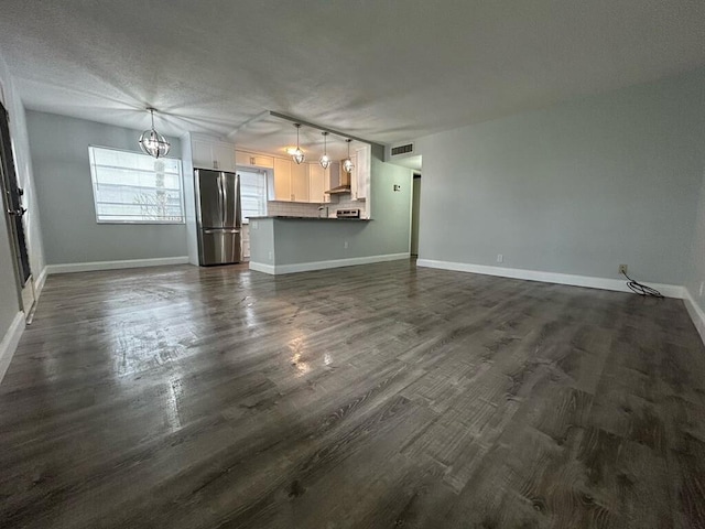 unfurnished living room with a textured ceiling and dark hardwood / wood-style floors